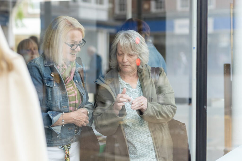 Two women being photographed through the window