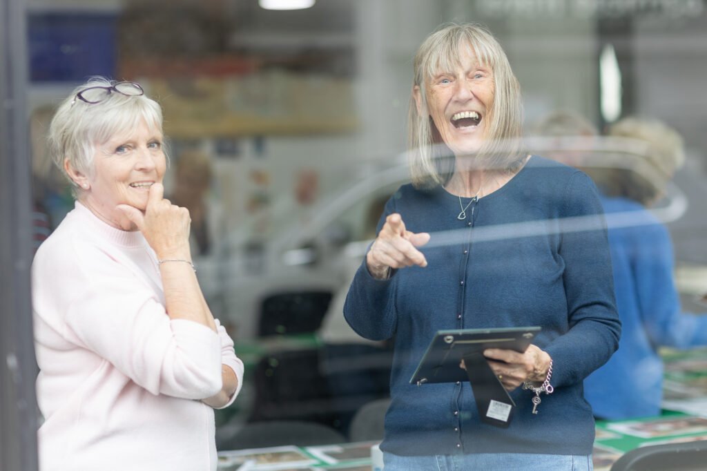 Two women being photographed through the window