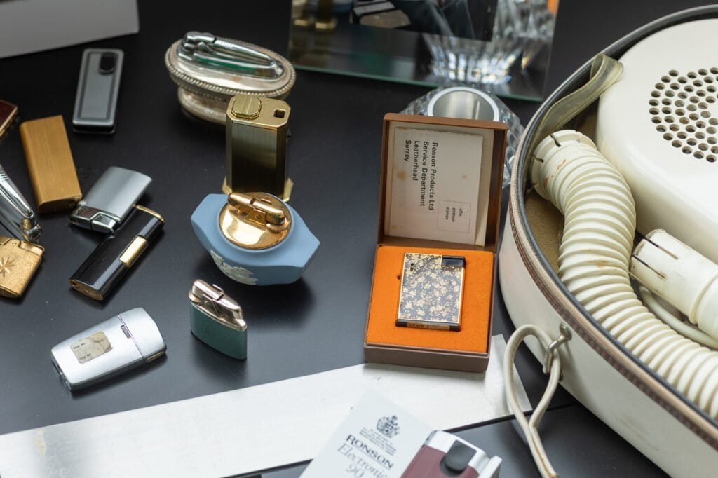 A black and gold patterned Ronson lighter in its box, with a card addressed to Ronson Products Ltd Service Department, Leatherhead.